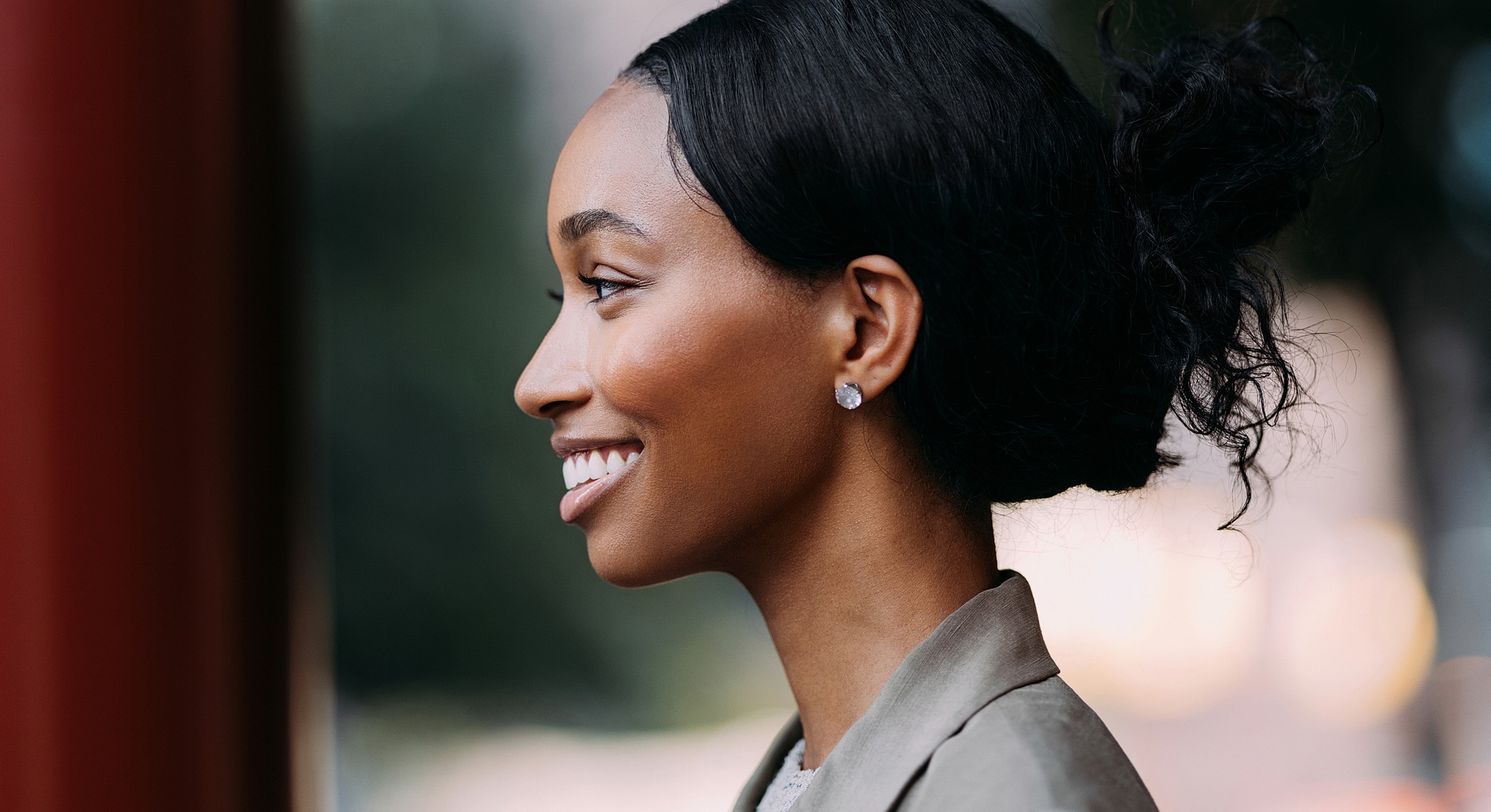 Woman smiling in profile against a blurred background.