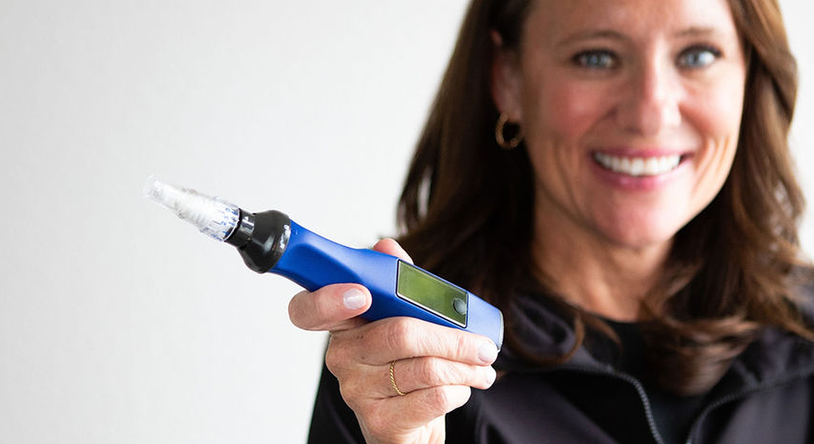 Woman holding a blue skincare device.